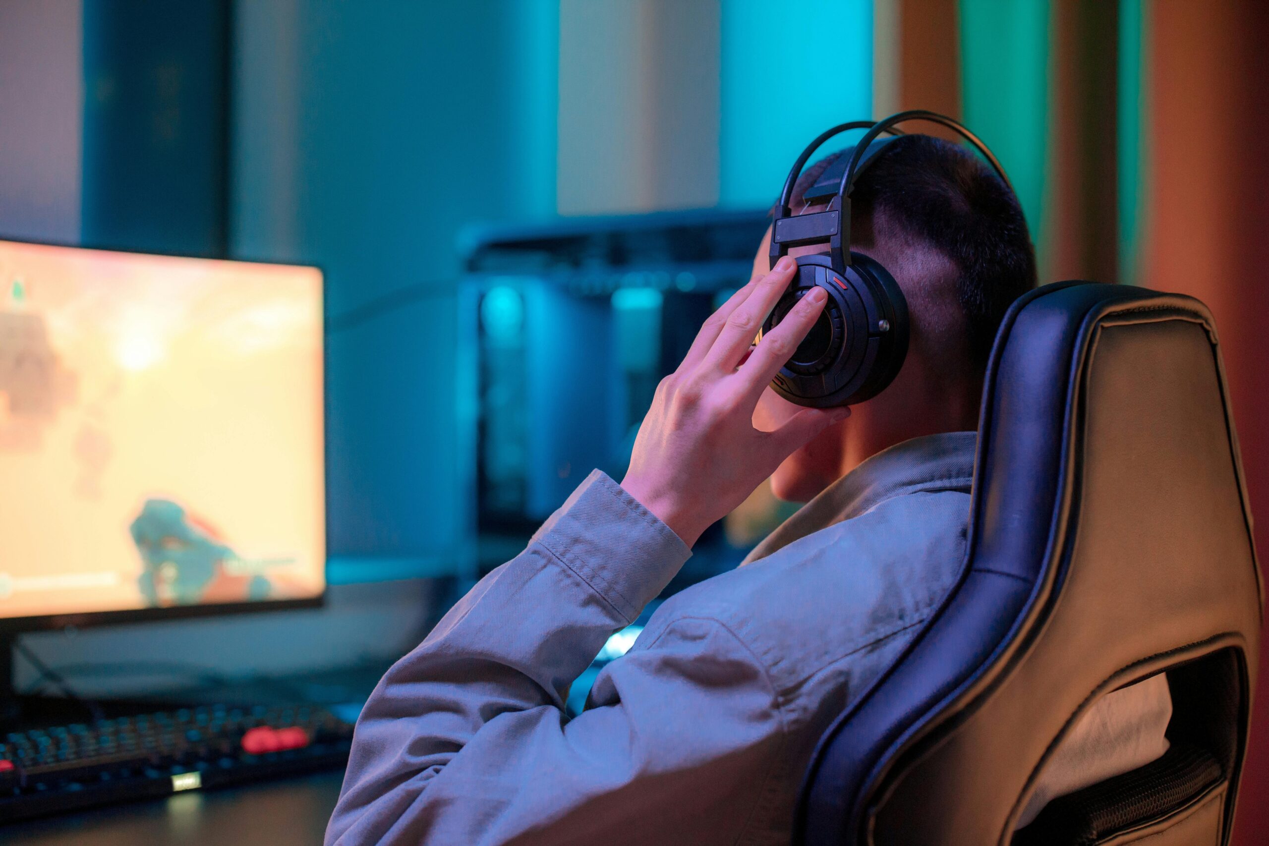 Desk setup featuring a gamer applying moisturizer while wearing headphones