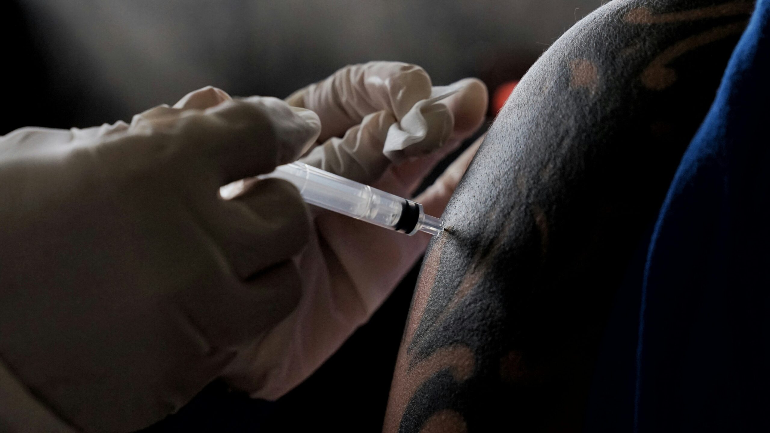 A gamer sitting comfortably while protecting their new tattoo during gameplay.