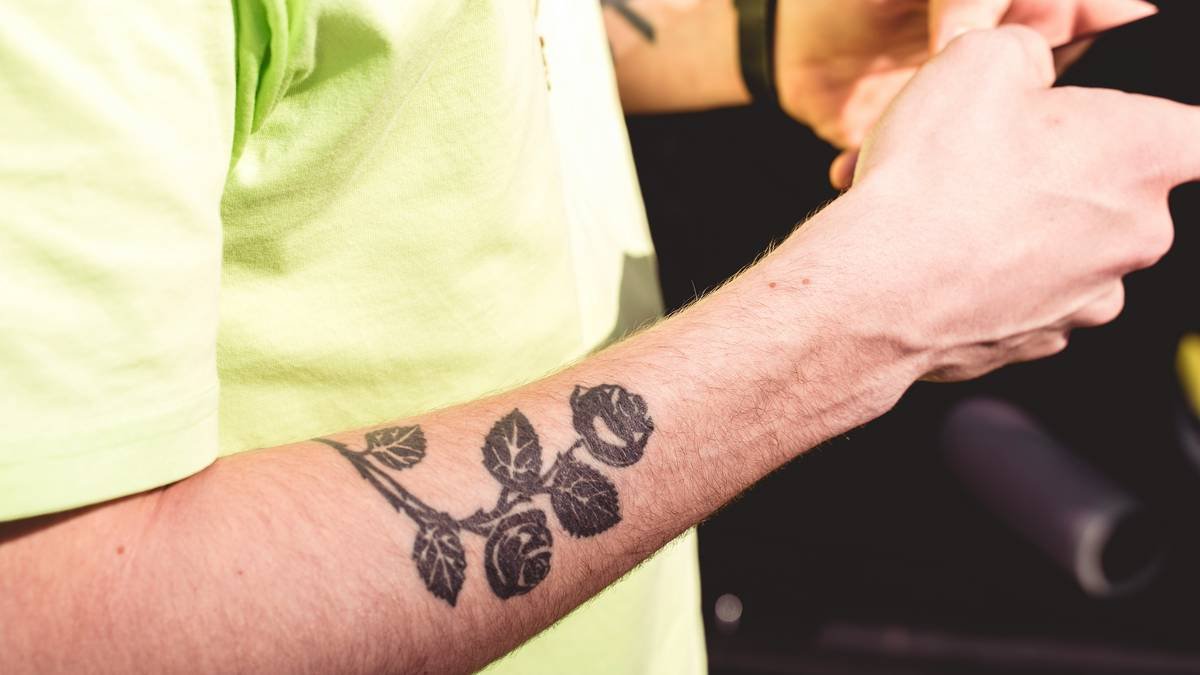 Side-by-side comparison: left shows generic chrome biomech tattoo; right shows authentic abstract gaming piece with melted SNES controller integrated into muscle tissue and circuit veins