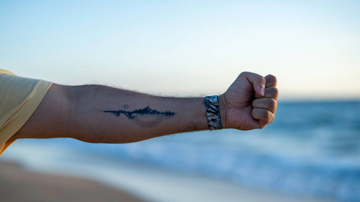 A man's arm with a tattoo of a shark on it