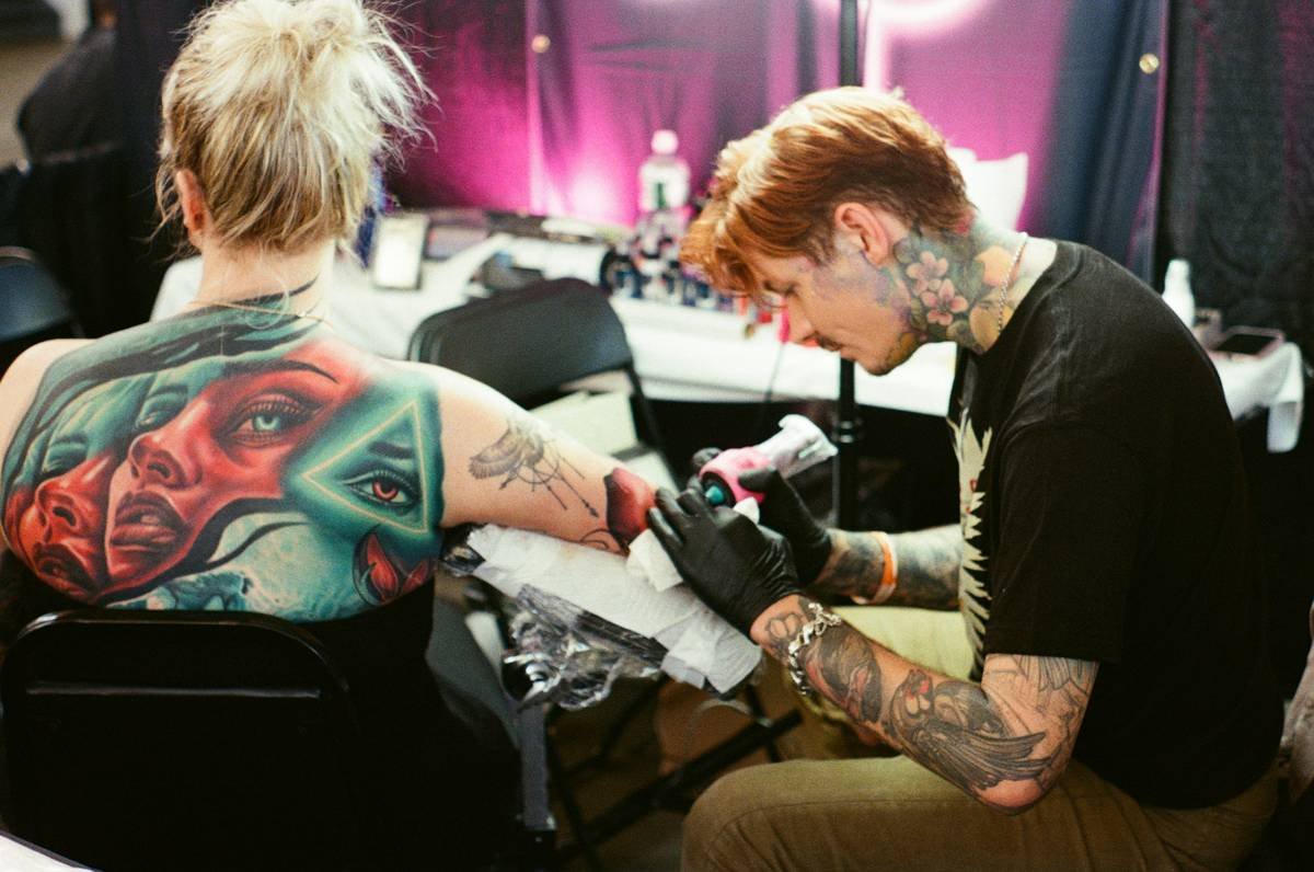 Tattoo artist working on a client's arm