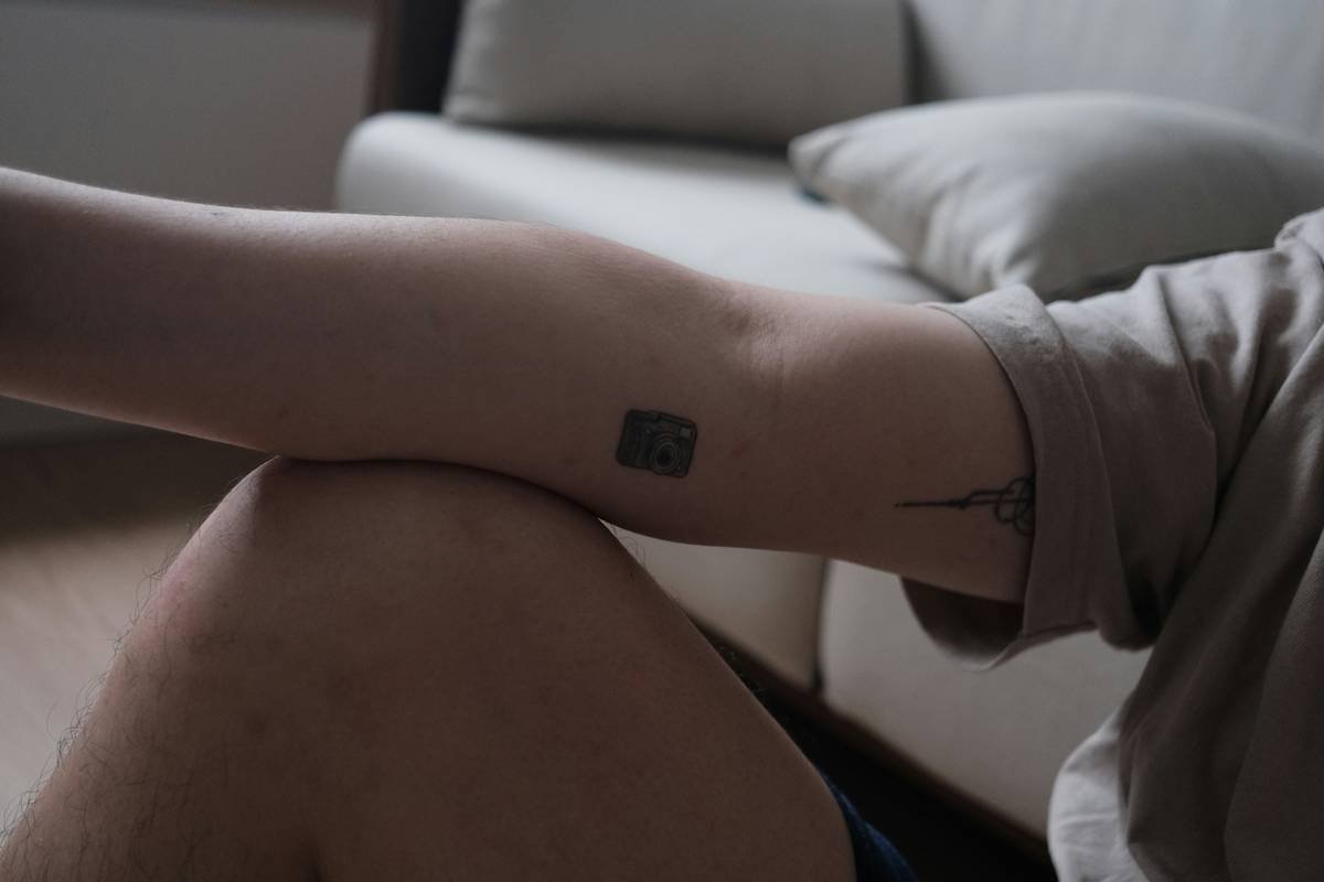 a person sitting on a couch with a tattoo on their arm