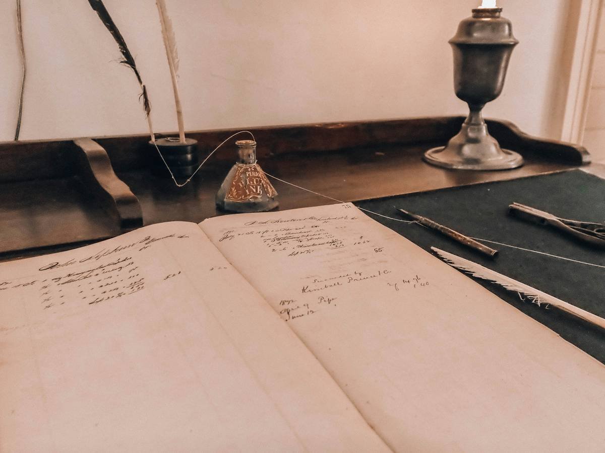 Vintage desk setup with an open ledger and writing implements.